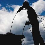 Chimney service in Manasquan being performed by silhouette of chimney sweep with brush in top of chimney